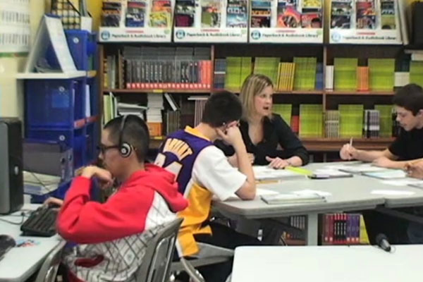 Students interact with a teacher in a classroom.